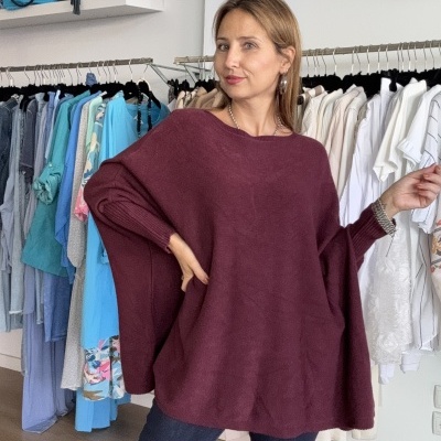 Mulher com camisola de malha vinho e jeans numa loja de roupa