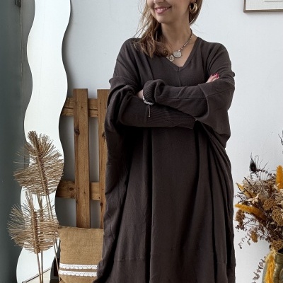 Mulher com vestido largo castanho e botas castanhas num interior com decoração natural