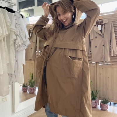 Mulher com casaco castanho claro e calças de ganga numa loja de roupa