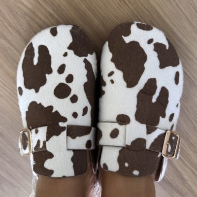 Sapatos mule com padrão de vaca castanho e branco com fivelas douradas
