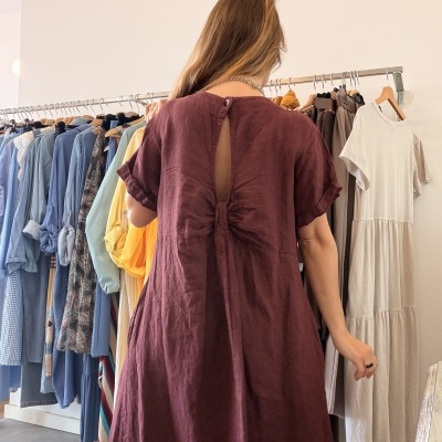 Vestido vinho com laço nas costas numa loja de roupa