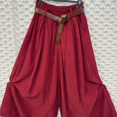 Calças largas vermelhas com cinto castanho penduradas num cabide