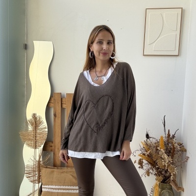 Mulher com camisola castanha com padrão de coração e palavra 'amour' em ambiente interior decorado