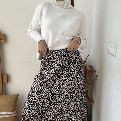 Mulher com camisola branca de malha e saia longa animal print