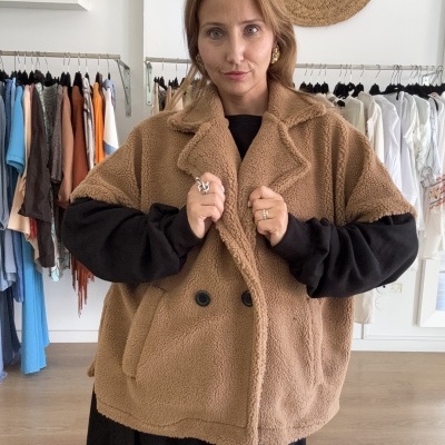 Casaco castanho tipo pelúcia oversize com botões pretos e gola de lapela sobre vestido preto