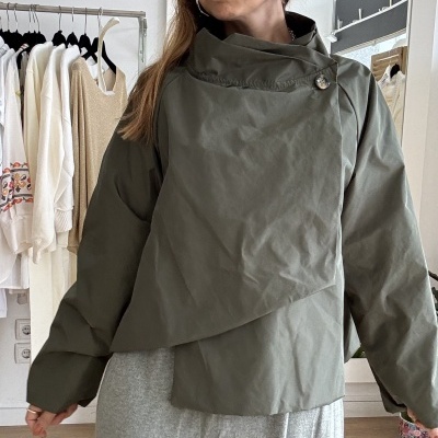 Casaco verde-oliva com gola alta abotoada e saia comprida cinza claro