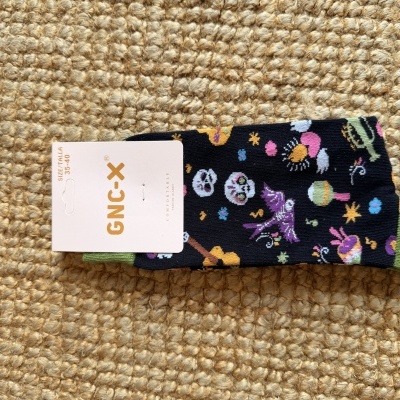 Meia colorida com etiqueta GNC-X sobre superfície bege texturizada