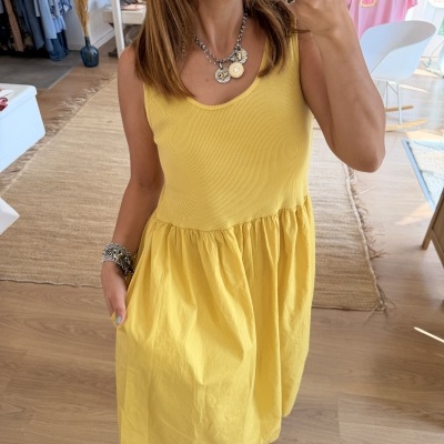 Vestido amarelo com parte superior canelada e saia lisa em loja de roupa