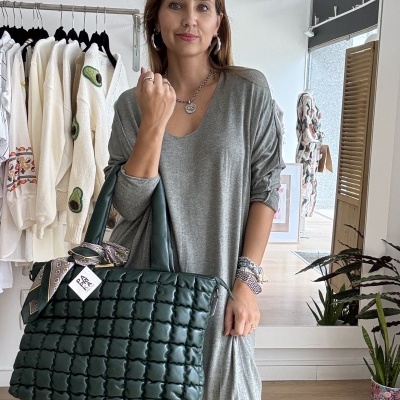 Mulher com vestido cinza claro e mala preta acolchoada numa loja de roupas