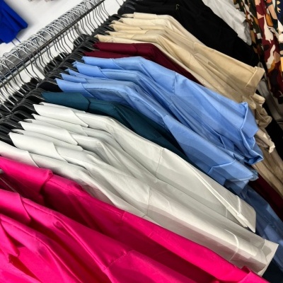 Várias camisas coloridas penduradas em cabides num varão
