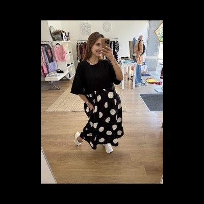 Vestido preto com bolinhas brancas grandes e manga curta numa loja de roupa