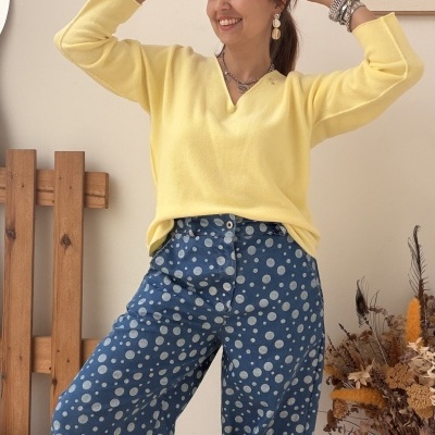 Mulher com camisola amarela e calças azuis de bolinhas num ambiente interior