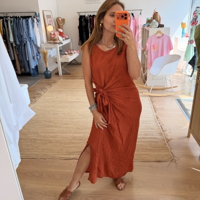 Vestido midi laranja com nó lateral numa mulher numa loja de roupa
