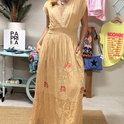 Vestido comprido amarelo claro com bordados florais usados por mulher em ambiente interior decorado.