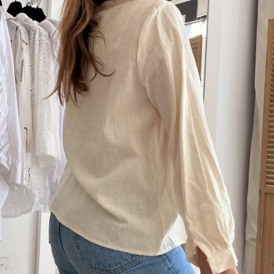 Mulher com blusa bege e calças de ganga em ambiente interior