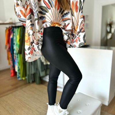 Pessoa vestindo blusa floral colorida, leggings pretas e sapatilhas brancas numa loja