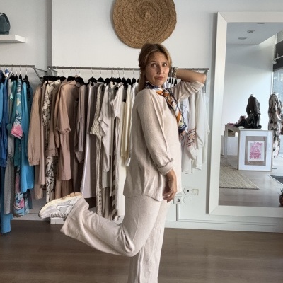 Mulher a usar roupa de malha bege com cachecol colorido e ténis brancos em loja de roupa