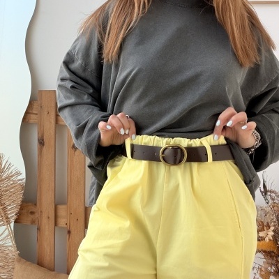 Mulher com camisola cinza e calças amarelas com cinto