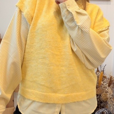 Pessoa com blusa amarela e camisa às riscas amarelas e brancas em ambiente interior