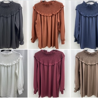 Seis blusas de manga comprida com gola franzida em diversas cores penduradas em cabides