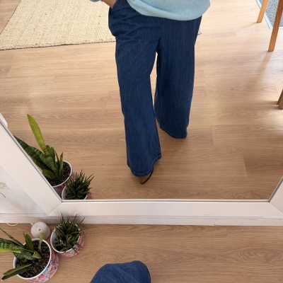 Calças largas de ganga azul escuras e camisola azul clara num ambiente interior