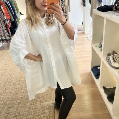 Mulher com túnica branca e calças pretas numa loja de roupa