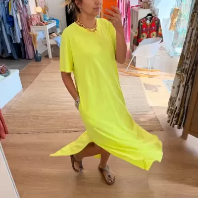Vestido amarelo fluorescente de tecido liso com manga curta e mulher a tirar selfie