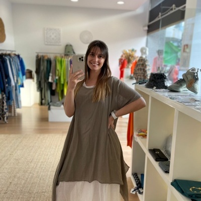 Mulher com vestido castanho claro e branco numa loja de roupas