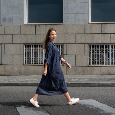 Mulher de vestido azul a caminhar numa passadeira de peões em cenário urbano.