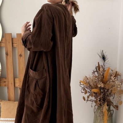 Vestido longo castanho com bolso e botas pretas em ambiente interior decorativo