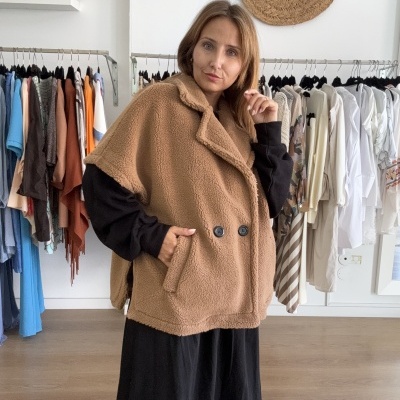 Casaco comprido sem mangas castanho claro de tecido peludo com dois botões e bolsos.