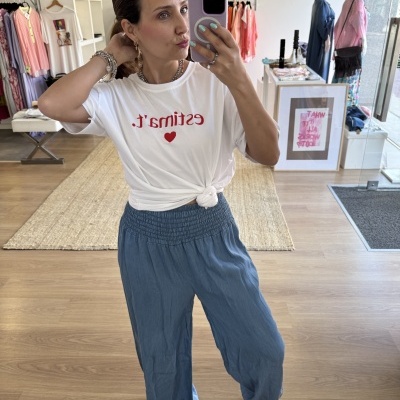 Mulher a tirar selfie com t-shirt branca e calças azuis numa loja de roupa