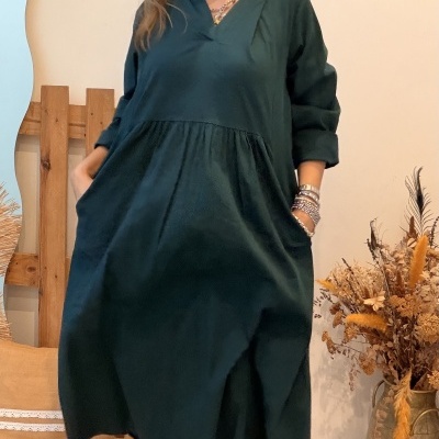Mulher com vestido azul escuro e botins castanhos em ambiente interior com decoração