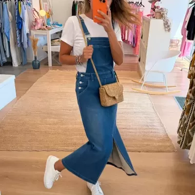 Mulher com vestido de ganga e t-shirt branca numa loja de roupa com telemóvel laranja