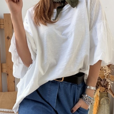 Mulher com camisa branca de tecido leve, calças de ganga azul e lenço verde no pescoço