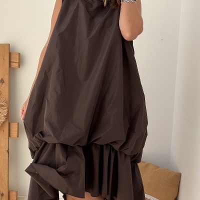 Vestido castanho escuro solto com botas castanhas dentro de um ambiente interior