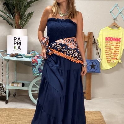 Mulher com vestido longo azul e cinto estampado em ambiente interior decorado