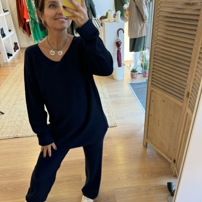 Pessoa a tirar selfie em espelho numa loja vestindo roupa azul escuro de malha com sapatilhas brancas