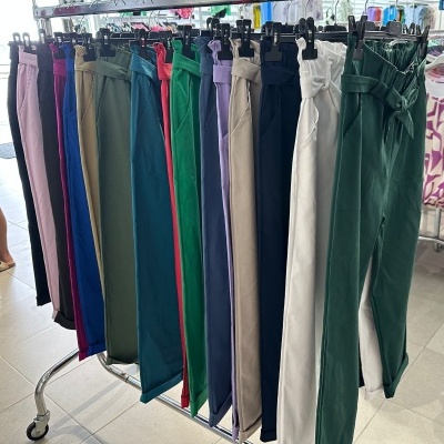 Várias calças femininas de cores diferentes penduradas num cabideiro