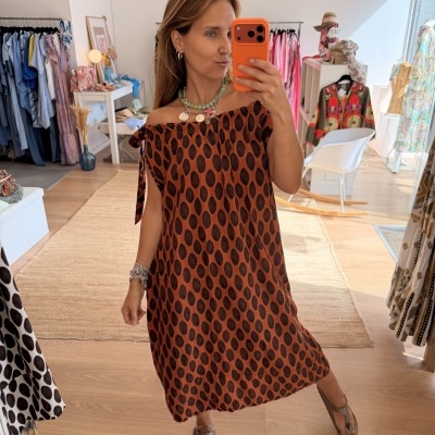 Vestido castanho com padrão de manchas pretas e decote ombro a ombro em loja de roupas