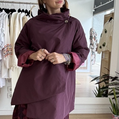 Mulher vestindo casaco bordeaux com saia floral em loja de roupas