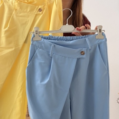 Mulher segurando calças amarelas e azuis em ambiente interior