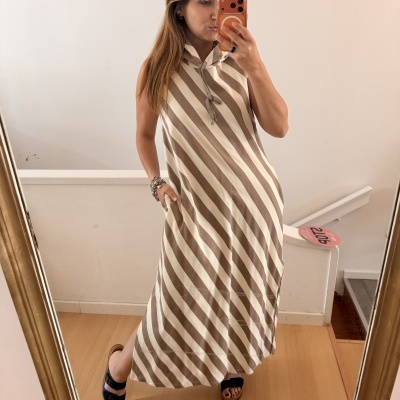 Vestido comprido listrado bege e castanho claro com capuz e cordão, mulher a tirar selfie num espelho