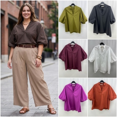 Blusas femininas de manga bufante em várias cores penduradas em cabides e blusa castanha usada por mulher com calças bege na rua