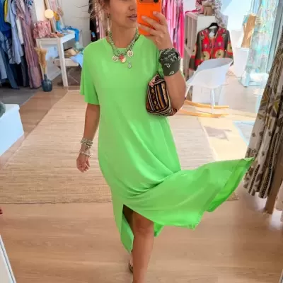 Mulher com vestido verde fluorescente manga curta em loja a tirar selfie