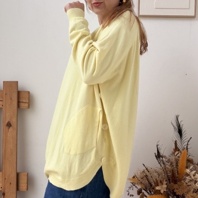 Mulher com camisola amarela e saia azul escura em ambiente minimalista