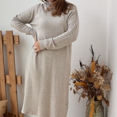 Vestido comprido cinza claro de malha com botas pretas em ambiente decorado