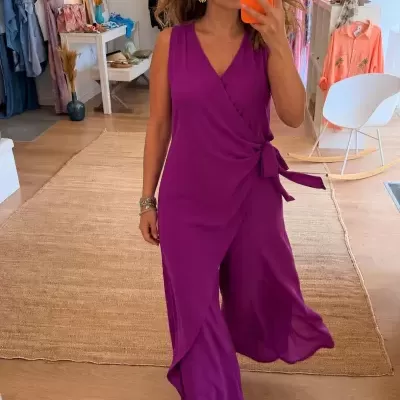 Mulher com macacão roxo e amarração lateral em loja de roupa