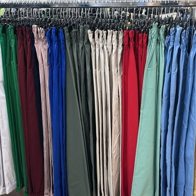 Calças coloridas de tecido penduradas em cabides metálicos numa loja