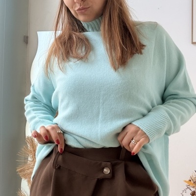 Mulher com camisola azul clara e calças castanhas